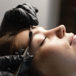 side-view-female-specialist-doing-eyebrow-treatment-woman